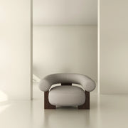 Modern armchair with curved upholstery and wooden legs in a minimalist interior space